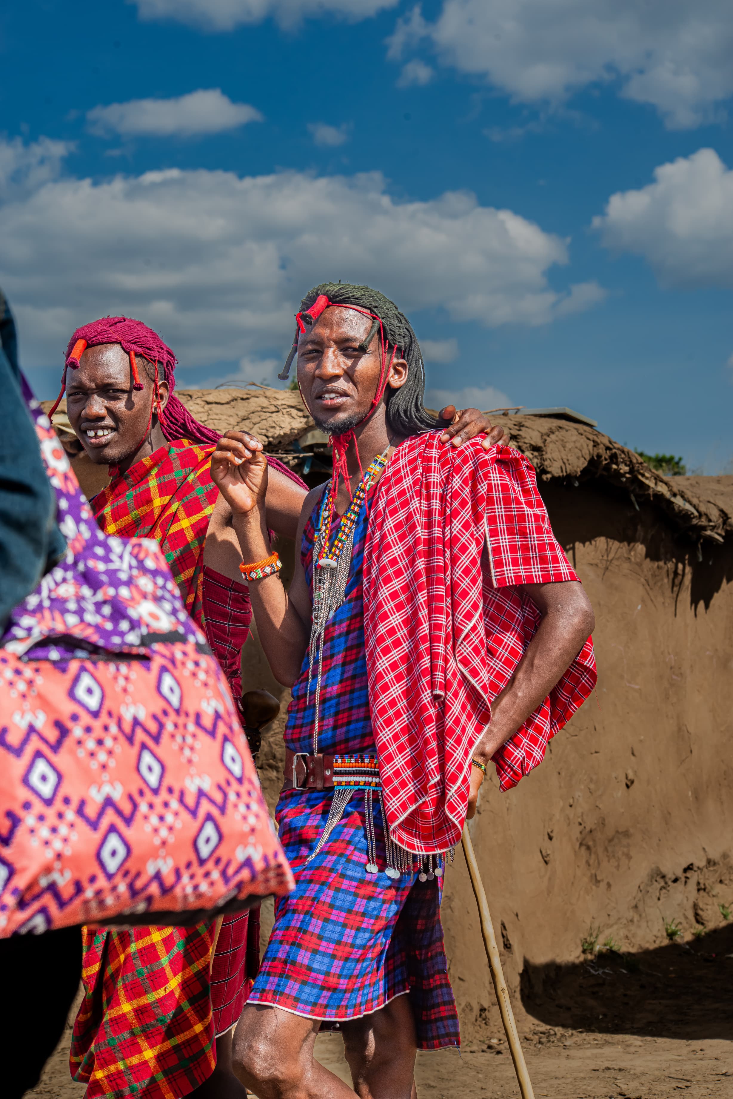 Maasai warriors in traditional red shukas and beaded jewellery during a cultural village visit in Kenya's Masai Mara ecosystem