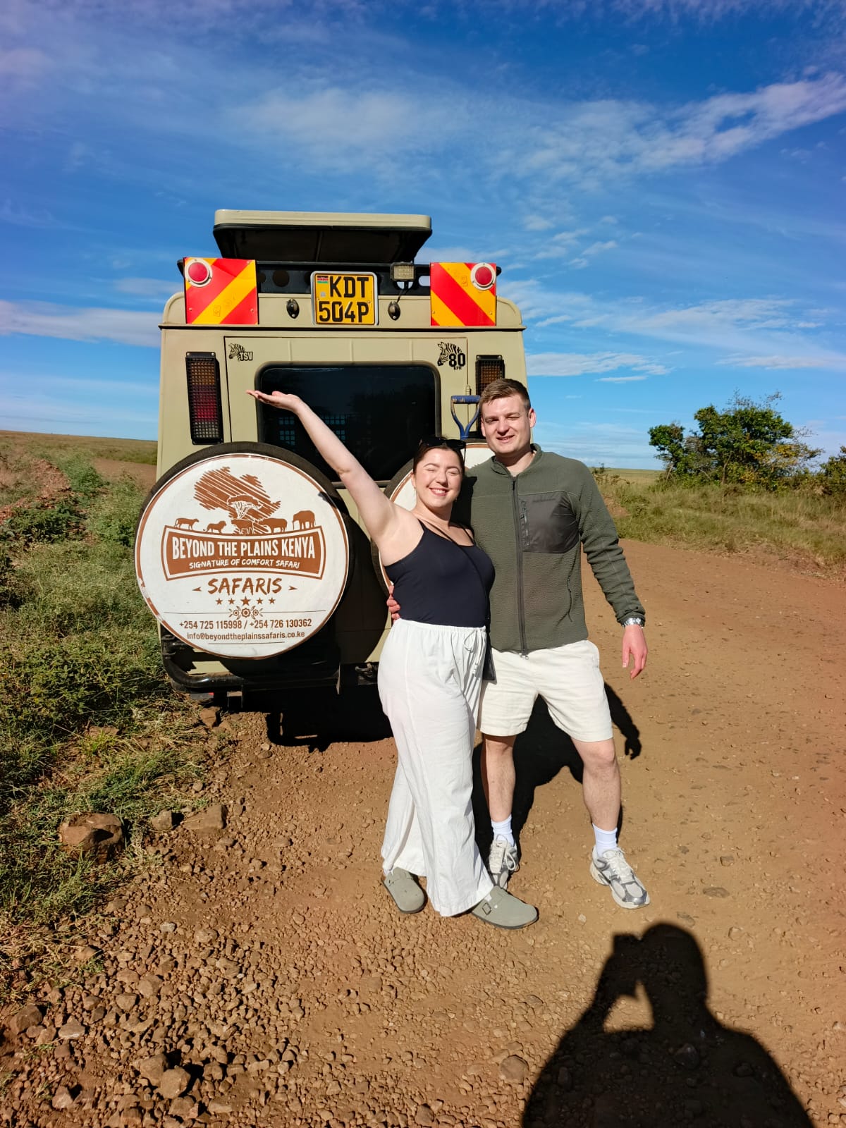 Beyond The Plains Safaris happy clients pose with branded safari vehicle in the Maasai Mara wilderness