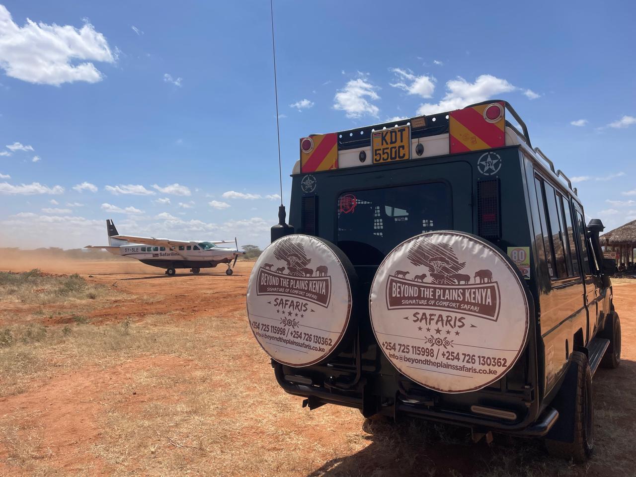 Beyond the Plains Kenya Safaris vehicle parked beside a bush plane on a remote safari airstrip, showcasing a fly-in safari experience in Kenya.