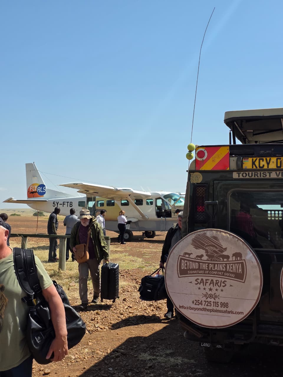 Travelers transferring from a bush plane to a Beyond the Plains Kenya safari vehicle at a Maasai Mara airstrip