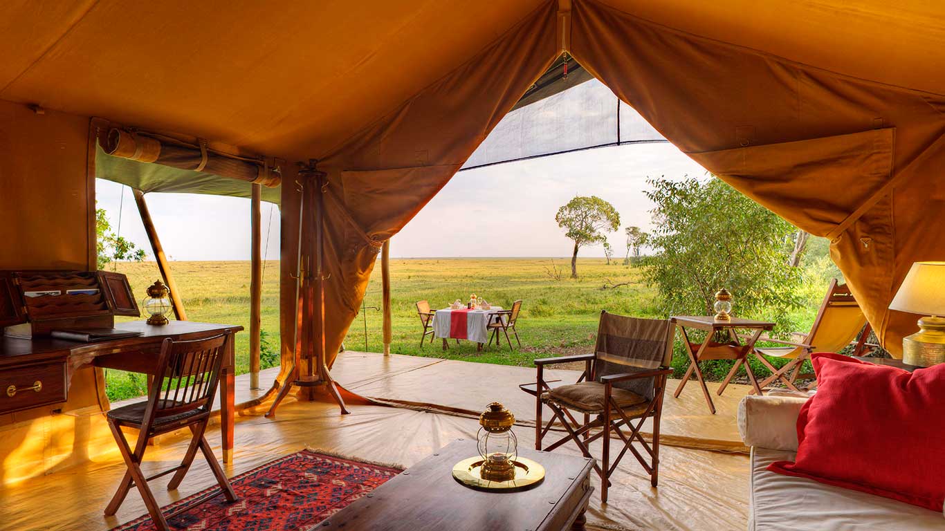 Interior of a luxury tent at Elephant Pepper Camp overlooking the Maasai Mara plains with outdoor dining setup.