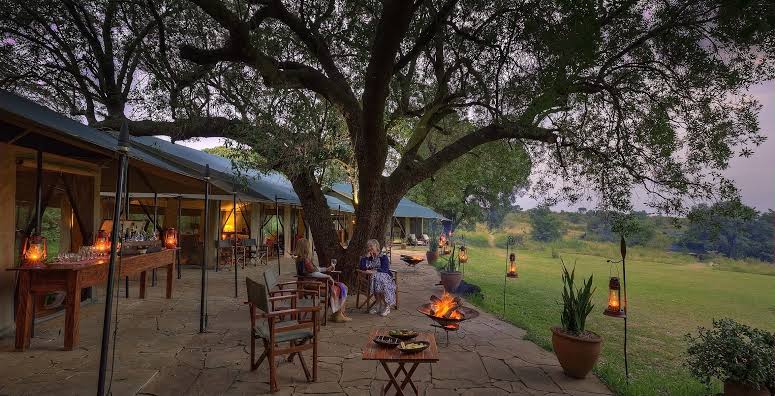 Outdoor lounge and campfire setting at Kicheche Mara Camp overlooking the Maasai Mara savanna at dusk.