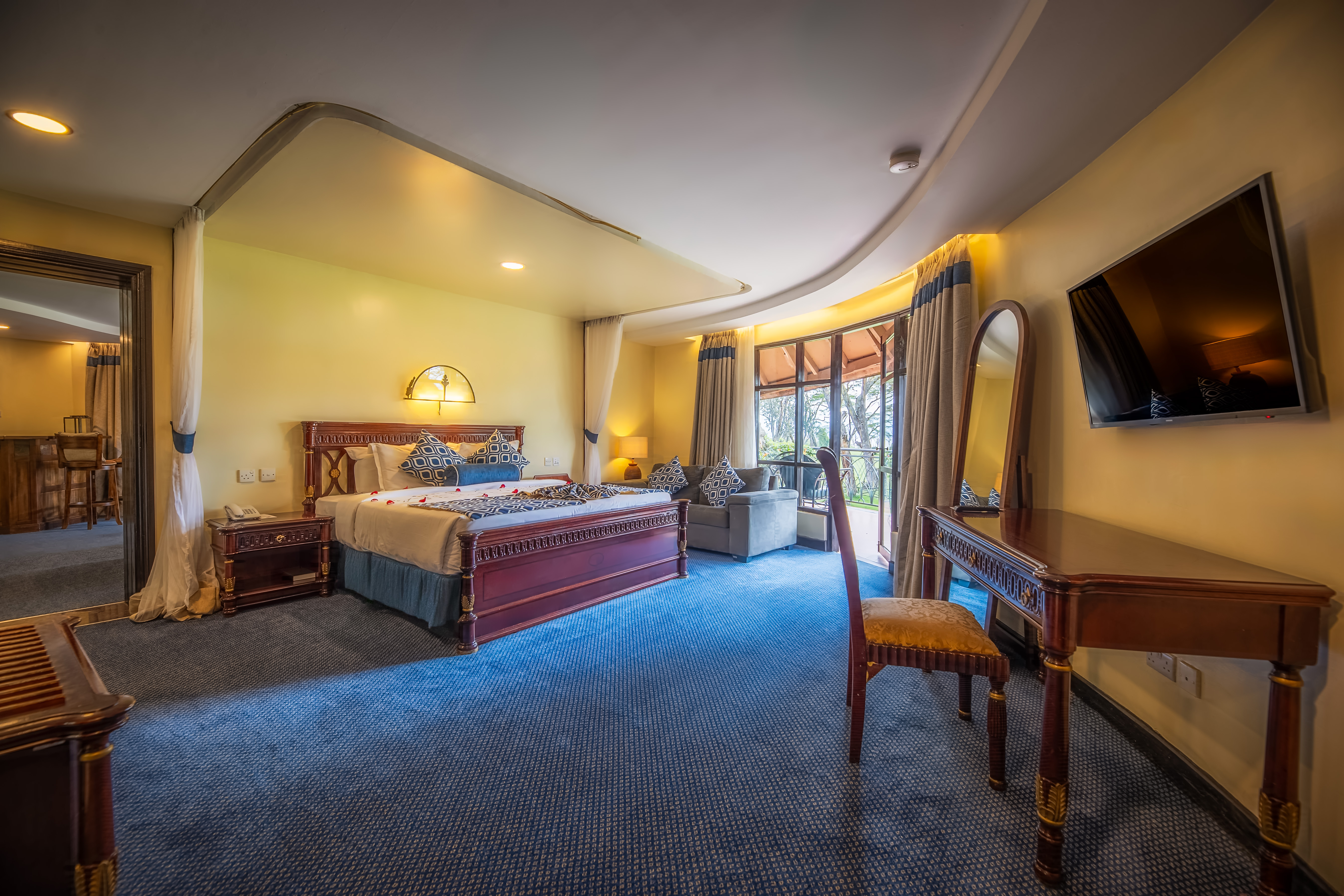 Spacious and elegant room at Naivasha Sopa with a large bed, cozy seating area, and warm ambient lighting.