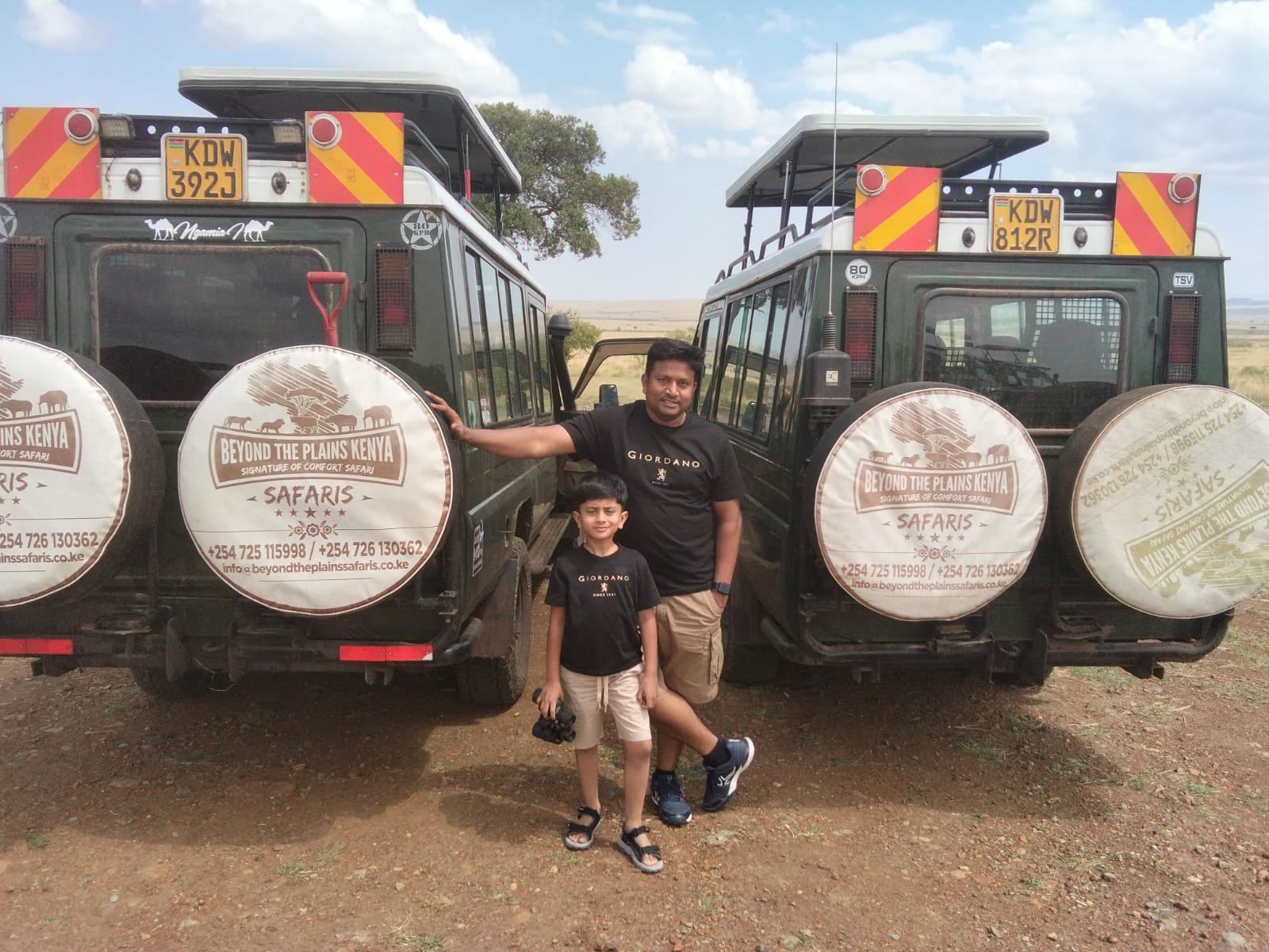 Father and son safari guests with Beyond the Plains Kenya vehicles in Maasai Mara