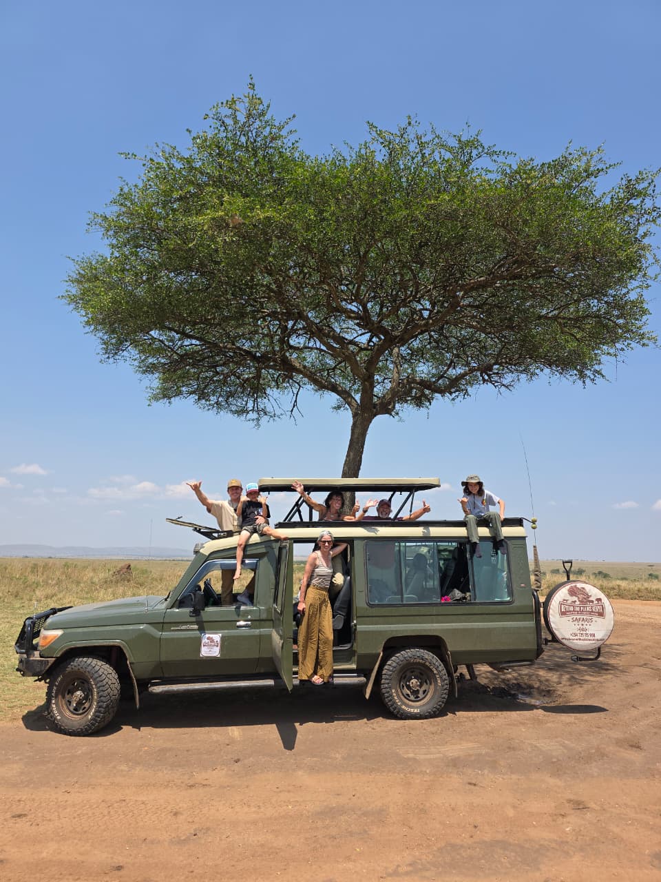 Travelers standing through the pop-up roof hatch of a Kenya safari Land Cruiser
