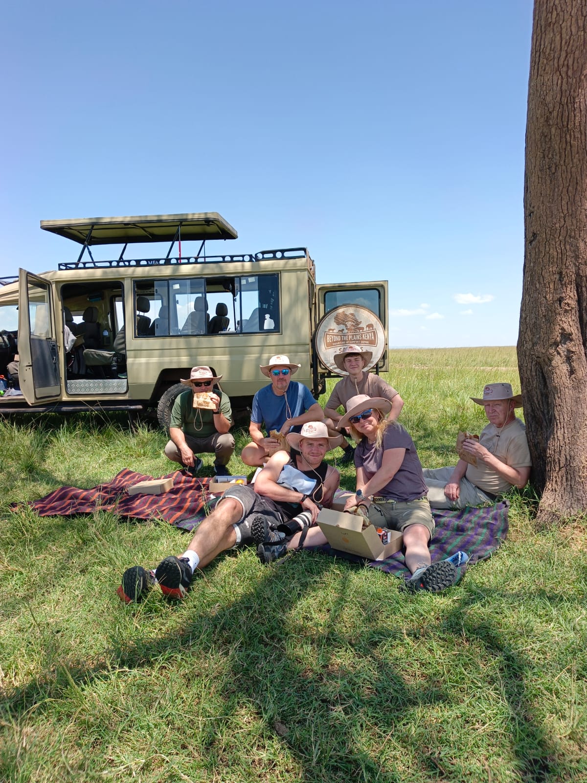 Safari group enjoying a bush picnic lunch beside their tour vehicle in Kenya