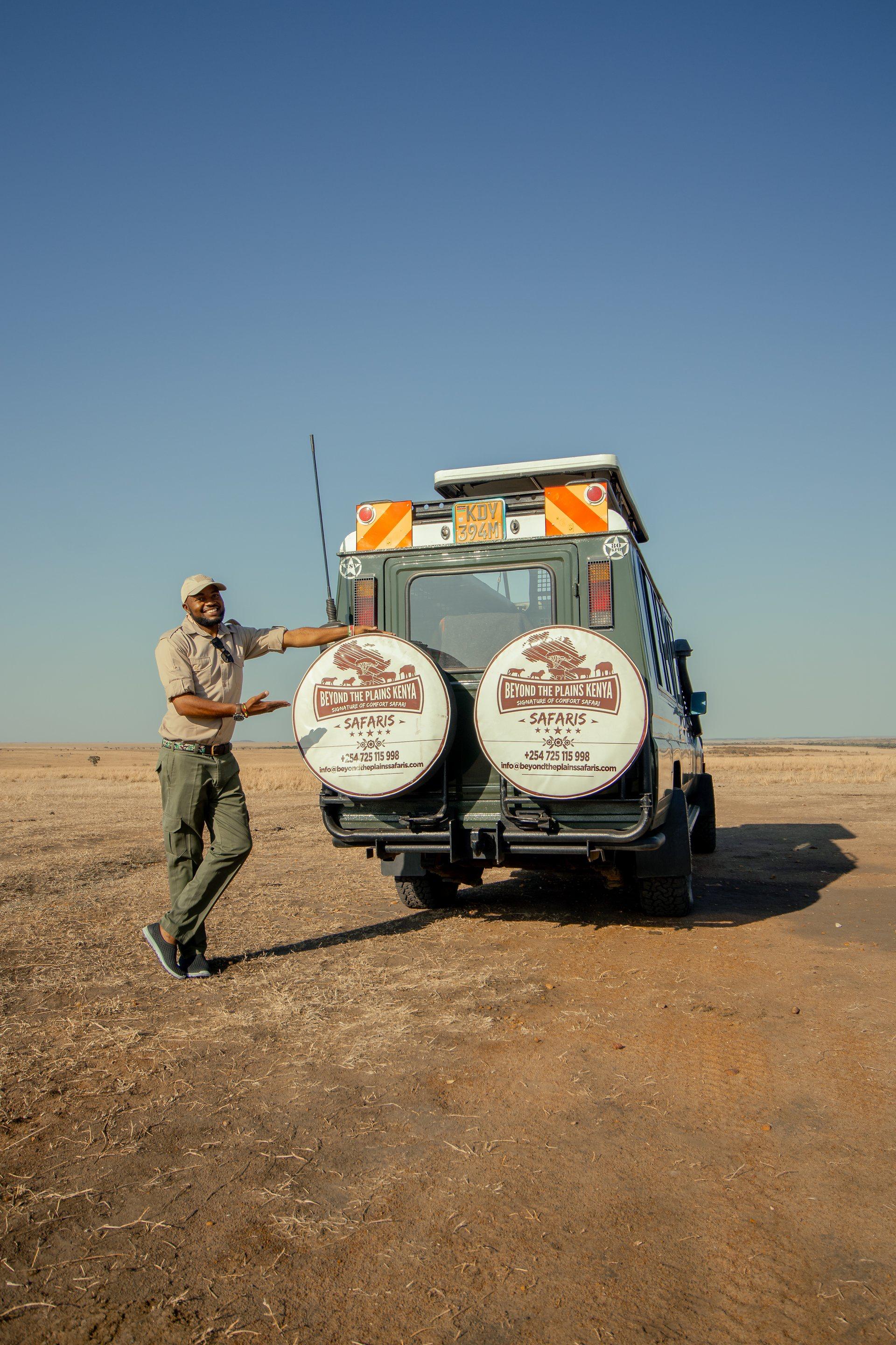 Douglas Onsongo, Beyond the Plains Safaris guide, standing beside a branded 4x4 safari vehicle in the Maasai Mara, Kenya